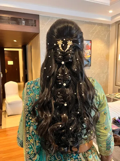 Soft and sophisticated curls with pearl embellishments. This hairstyle is perfect for a reception or sangeet, adding a touch of romance and glamour.