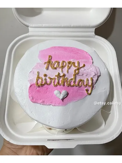 An artistic birthday bento cake with pink brushstrokes and elegant gold lettering.