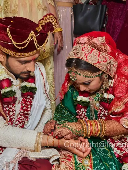 This photo focuses on the details of the ritual itself. The composition draws attention to their hands, the bride's green Bandhani saree, and the groom's velvet turban.