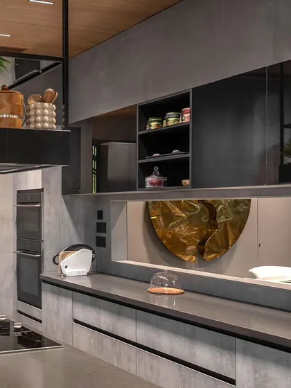 The modern, industrial-style kitchen in the 'Nadhyavart' project. A long ribbon window connects the kitchen to the dining area, fostering visual continuity and maintaining the design's ethos of openness.