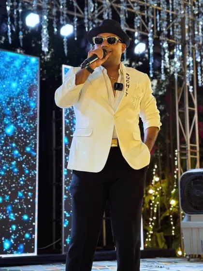 On the mic, in my element. The white blazer and hat combo gives off a cool, confident vibe, perfect for an evening of entertainment.