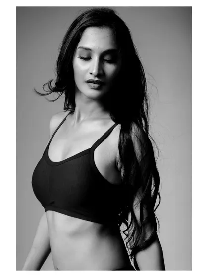 A black and white portrait of a model in activewear. The lighting emphasizes the model's strength and athletic form.