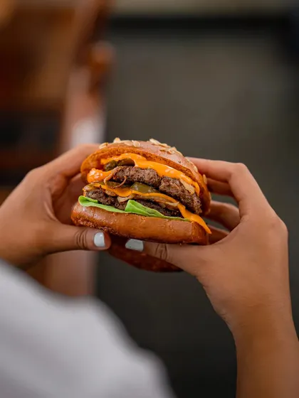 A close-up of our double-patty smashed burger, showcasing the perfectly melted cheese and juicy meat. We focus on the perfect meat-to-fat ratio for a melt-in-your-mouth texture.
