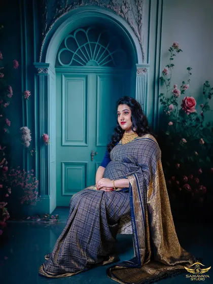 A regal, seated portrait of the mother-to-be in her beautiful saree. The artistic backdrop and her confident pose create a powerful and elegant image.