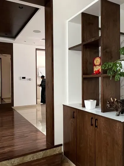 A custom wooden partition and shelving unit in the 'Hongirana' residence, which defines the entryway while maintaining an open and connected feel.