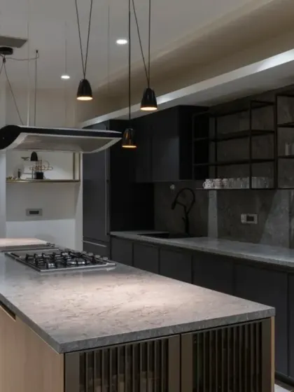 The Screen House boasts three kitchens, one on each level. The ground floor kitchen is the most spacious, with a sleek, modern design in a sophisticated palette of black and beige, centered around an island with elegant pendant lights.