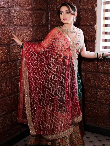 A model posing by a window in a beautiful lehenga. The warm, natural light and her elegant posture create a sophisticated and timeless fashion portrait.