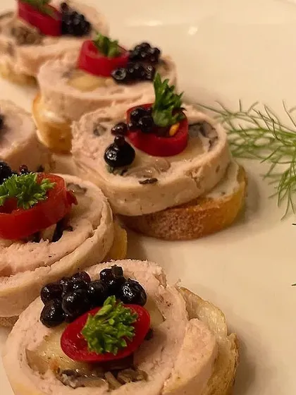 A close-up of our chicken and mushroom roulade canapés. These intricate bites are served on a toasted bread base and garnished with cherry tomato and caviar for a touch of elegance.