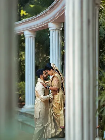 Peeking through architectural pillars to capture a private moment. This framing technique adds depth and a sense of intimacy to the couple's portrait.
