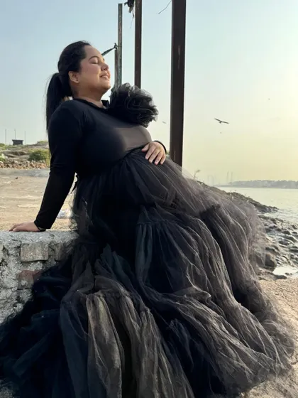 This black tiered gown combines comfort and style with its full-sleeved top and voluminous net skirt. It's a versatile piece that works for both studio and outdoor shoots.