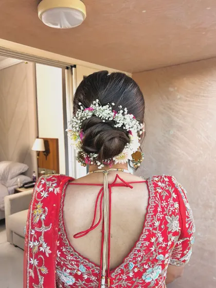 A classic low bun wrapped in a garland of baby's breath and other small flowers. This is a timeless and romantic choice for any bride or bridesmaid.