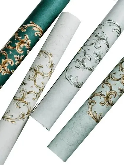 A collection of four wallpaper rolls with a classic scroll design, in green, white, and light blue with gold or silver accents.