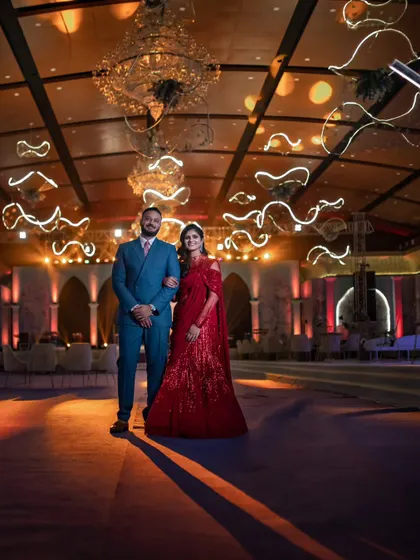 A grand portrait of the couple at their reception. The wide angle shows off the magnificent venue decor, with the couple standing confidently at the center of it all.