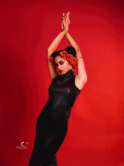 A powerful and expressive pose with arms raised. The floral hairpiece becomes a central focus, adding a touch of surreal beauty.