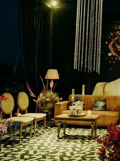 I create intimate and stylish lounge areas for guests to relax. This cozy corner features a plush sofa, elegant seating, and a dramatic art backdrop, all illuminated by a cascading crystal chandelier.