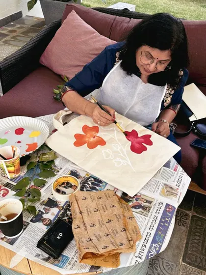 A participant at a family art event painting a floral design on a tote bag. Our workshops can be customized to include a variety of crafts.