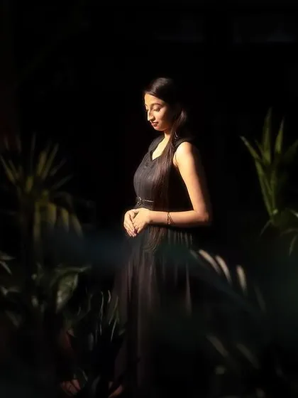 A moody and artistic solo portrait of the bride in a garden at night. The play of light and shadow creates a sense of quiet contemplation and elegance.