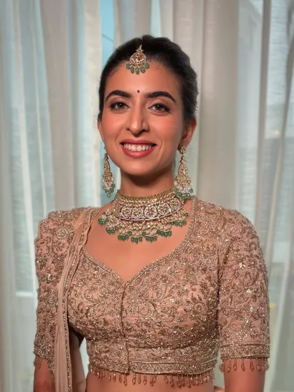 A beautiful, happy bride in a peach-golden lehenga. The makeup is kept soft and natural to let her joy shine through.