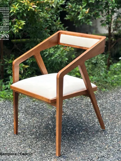 A full view of the Zircon chair, showcasing its sleek, angular design and the beautiful contrast between the warm teak wood and the light-colored upholstery.