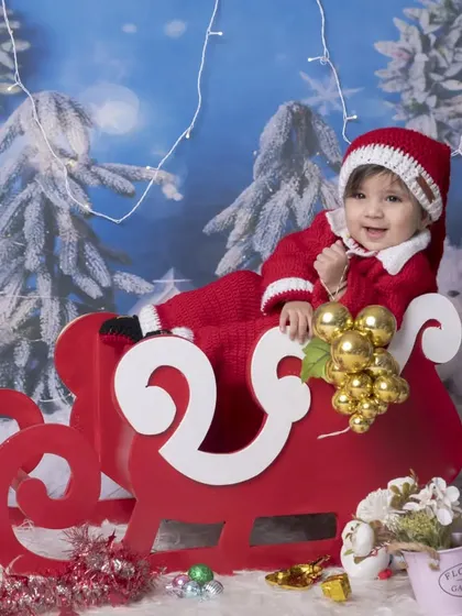 A happy baby Santa enjoying a sleigh ride in my winter wonderland studio setup. The twinkling lights and snowy backdrop make this a truly festive portrait.