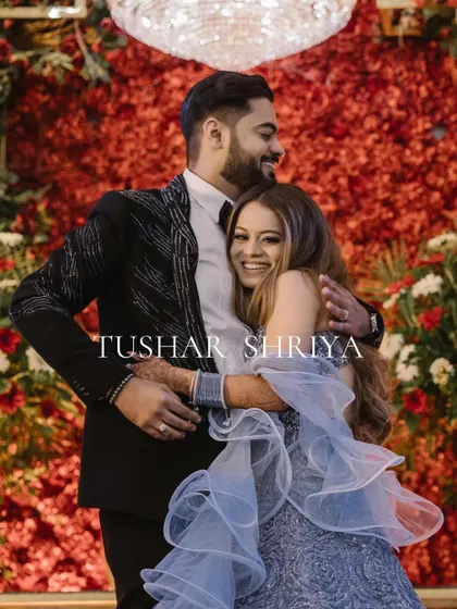 A heartwarming, candid moment of Tushar and Shriya sharing a hug against a vibrant red floral backdrop. Their genuine happiness is infectious.