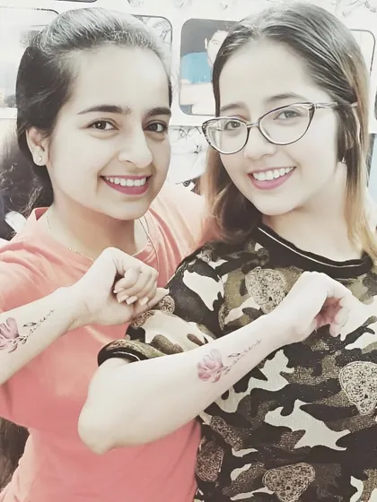Friends with matching watercolor lotus flower tattoos on their forearms.