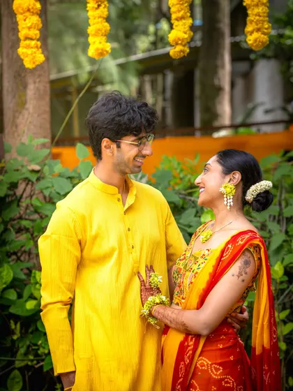 A sweet portrait of the couple during their Haldi ceremony, surrounded by lush greenery and traditional yellow floral decor.