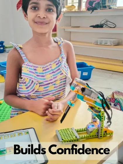 A young girl confidently shows off her robotic arm project, which she programmed to move and interact with objects.