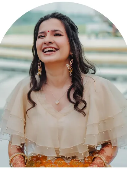 A joyful, candid moment highlighting the delicate, multi-layered organza cape blouse. The pearl drop detailing along the edges adds a subtle touch of elegance.