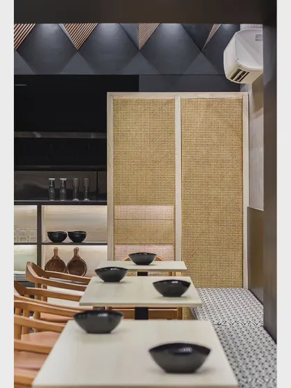 The minimalist side of the Japanese restaurant, featuring clean lines, natural textures like rattan screens, and a monochromatic color scheme that creates a calm and orderly dining space.