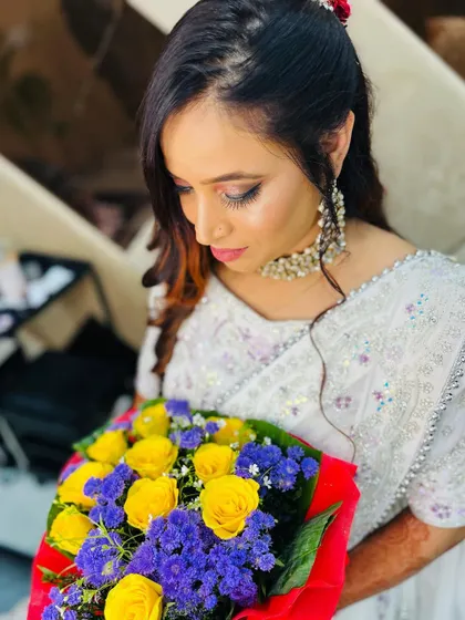 A soft and romantic party look. The client's makeup is dewy and fresh, and she looks beautiful holding a bouquet of flowers.