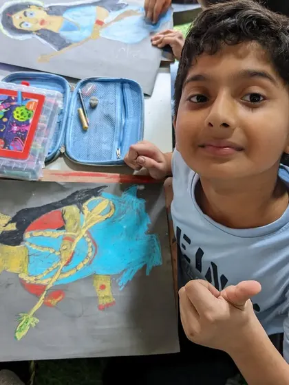 A young artist with his vibrant oil pastel drawing of a deity. He has used bold colors to make his artwork stand out.