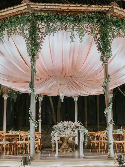 For this garden reception, we created a romantic dining experience inside a beautiful gazebo. The soft pink drapes and lush greenery created an intimate and elegant setting for the couple's celebration.