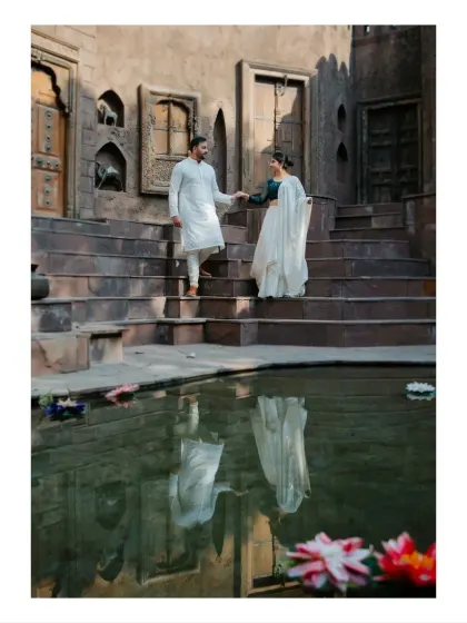 A classic pre-wedding pose of a couple descending the steps of a traditional stepwell. The reflection in the water adds a layer of depth and artistry to this heritage-themed portrait.