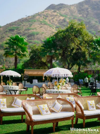 Cane sofas with custom-printed cushions, set against the beautiful backdrop of the Aravali hills for a relaxed haldi celebration.