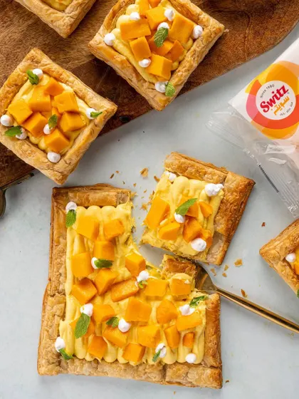 A flat-lay of mango puff pastries for Switz. This style of food photography is great for website banners and social media, showing the product in a bright, clean, and appetizing context.