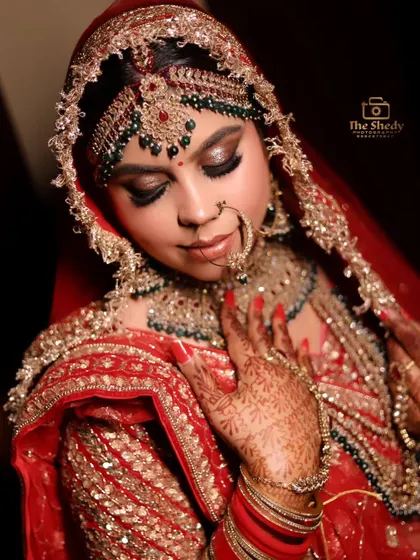 A stunning close-up of a bride, highlighting her dramatic eye makeup and the intricate details of her maang tikka and nath.