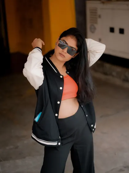 A portrait of a model in a varsity jacket, looking over her shoulder. The urban setting and her cool demeanor create a stylish and confident shot.