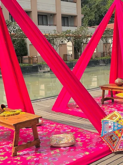 A low seating area for the Haldi rituals, with bright pink drapes and a patterned rug. This creates a comfortable and traditional space for the core ceremonies.