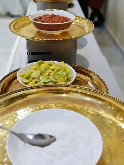 The small details matter. We provide all the necessary accompaniments like fresh lemon, salt, and homemade pickles to complete the traditional Indian meal.