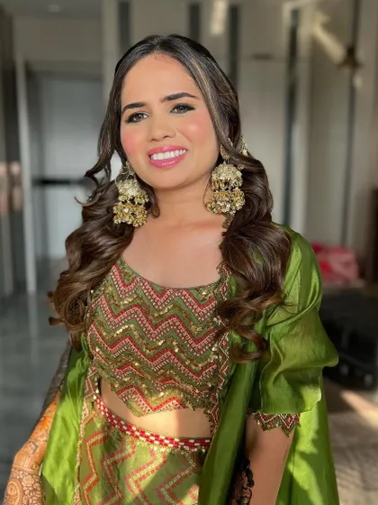 A beautiful Mehendi look featuring a stunning green outfit by Punit Balana. The makeup is kept fresh and glowing with a pink lip to complement the vibrant colours.