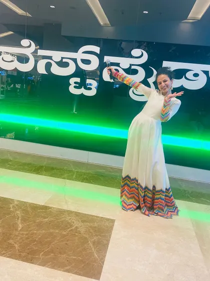 Anchor Nisarga Gowda looking cheerful in our white and multi-color chevron gown while hosting a mall event. This outfit is available for rent.