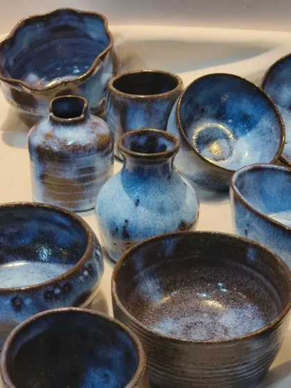 Another view of the finished glazed pottery, showing a variety of forms including bowls, vases, and cups. Our glazing lessons help you bring your pieces to life with color.
