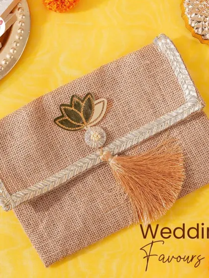 A jute clutch with a lotus motif and tassel, a perfect and stylish return gift for a mehendi or haldi ceremony.
