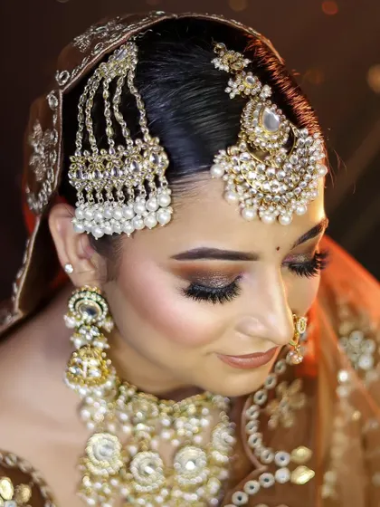 A close-up of a different bridal look in the same warm color palette, focusing on the eye makeup and passajewelry.
