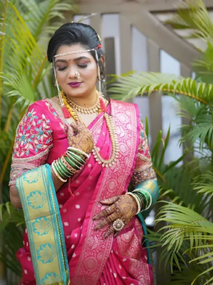 The bride looking elegant in her pink Paithani saree, complete with green glass bangles and a traditional nath.
