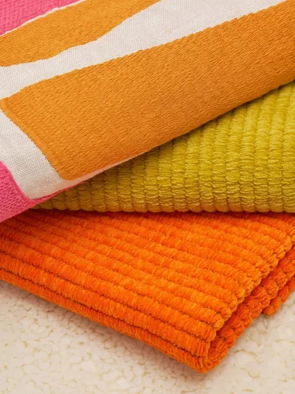 A close-up of richly textured, colorful fabrics from Élitis. The image highlights the plush, corduroy-like weaves and bold embroidered patterns that add a tactile dimension to any design.