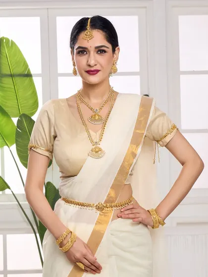 Full view of the model in a white and gold saree, adorned with a complete traditional gold jewellery set, including a waist belt (kamarbandh).