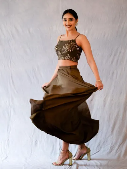 A full-length studio shot capturing a moment of happy movement. The flowing skirt and bright smile create a fun and energetic portrait, perfect for fashion or lifestyle photography.