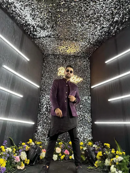 Posing in a cool, modern purple bandhgala jacket against a lit-up, glittery backdrop. This look is perfect for a glamorous cocktail night or sangeet.